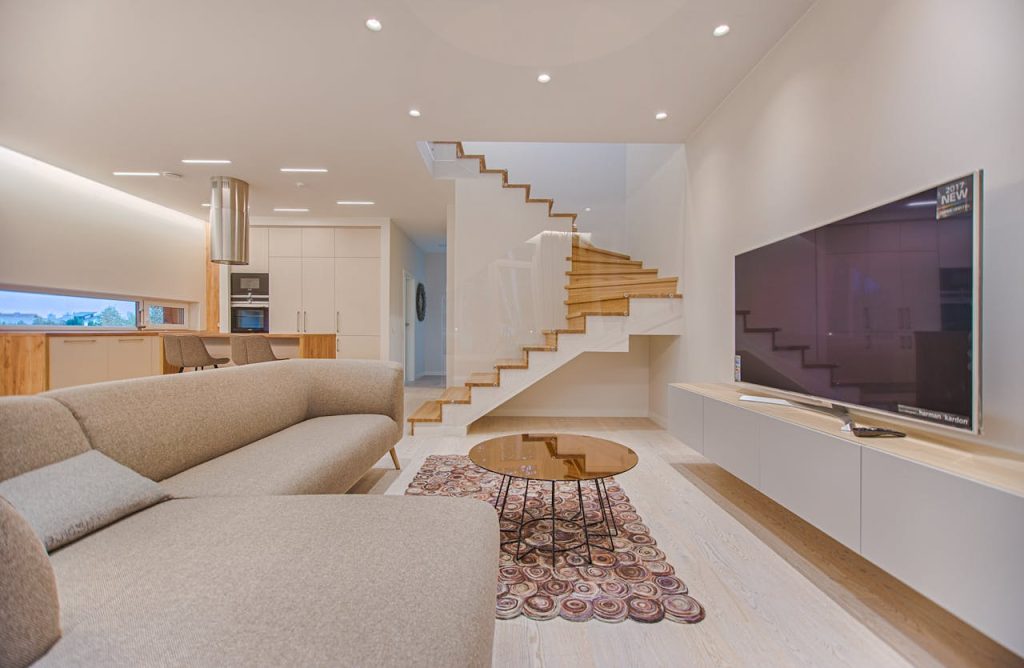 turned-on-gray-flat-screen-smart-tv-1571459 Spacious modern living room featuring stairs, a TV, and sleek furniture design.